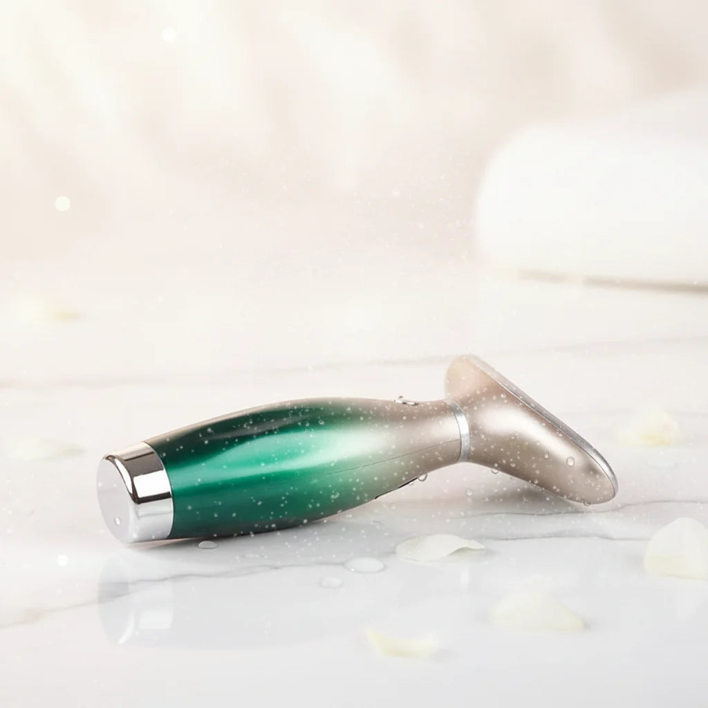 Appareil de beauté EMS micro-courant, design ergonomique vert dégradé avec finition argentée, posé sur une surface marbrée